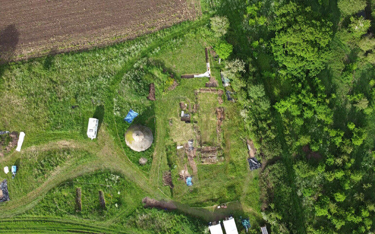 Aerial shot of an archaeological site showing a field and medieval chapel in Che