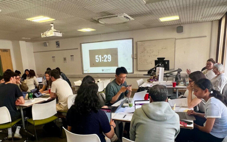 Students working in groups around tables as part of a Lightning Hack event