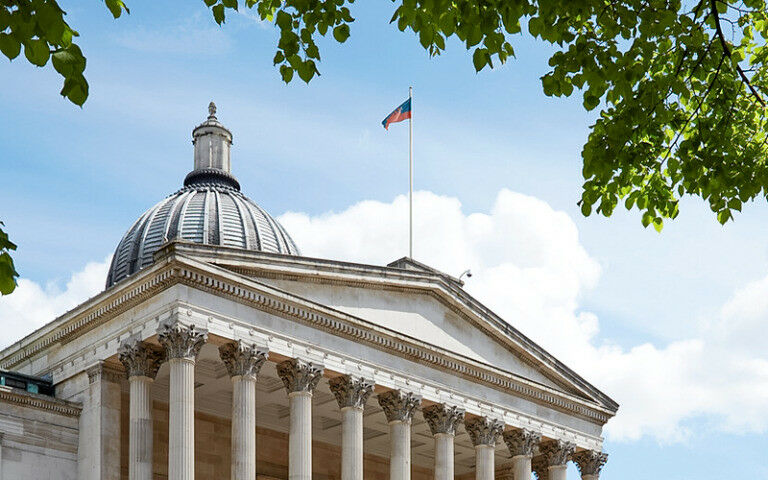 The UCL Quad pillars with a blue sky and green tree leaves behind them