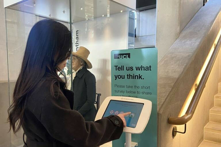 A photo of a young woman using a CampusVibe terminal at the UCL Student Centre