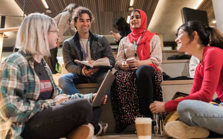 Four students talking and laughing together in UCL’s Student Centre