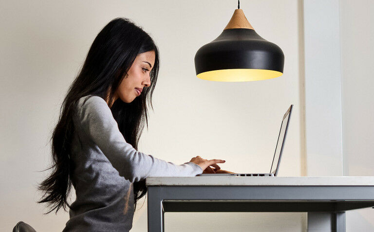 A person looking at their laptop sat at a desk