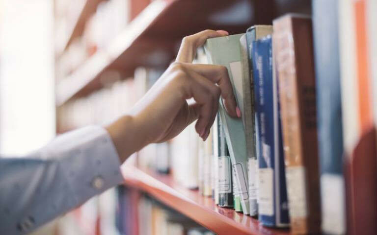 Hand taking a book from shelf