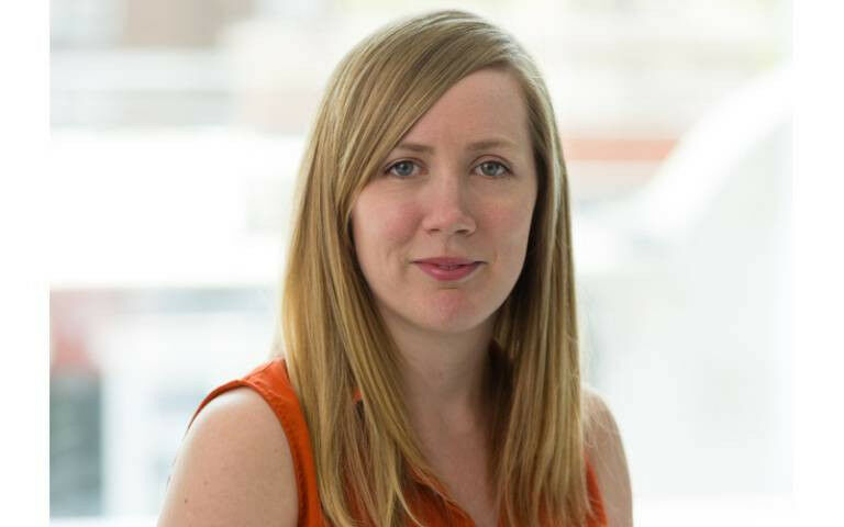 Lydia Harwood, wearing an orange vest top and looking towards the camera with a