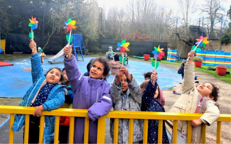 A group of children holding miniature windmills from the Welcome Parties, standi